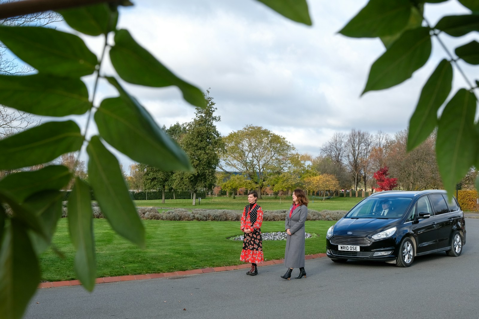 a couple of women standing next to a black car